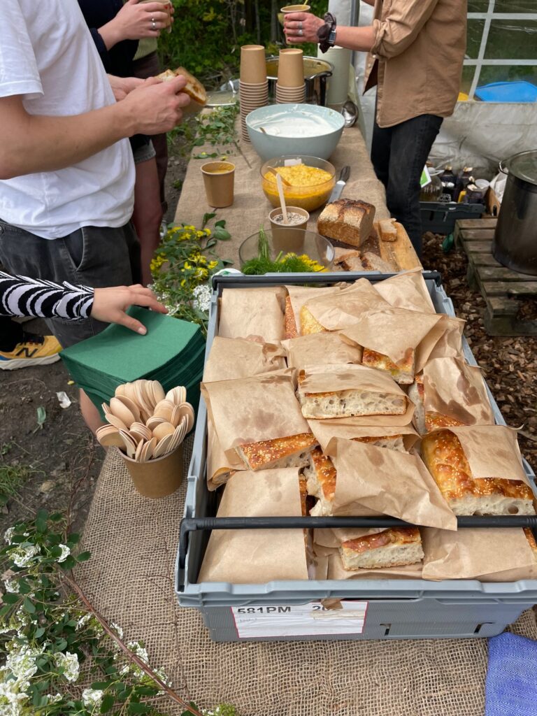 A table with a box of focaccia, wooden utensils, napkins, condiments
