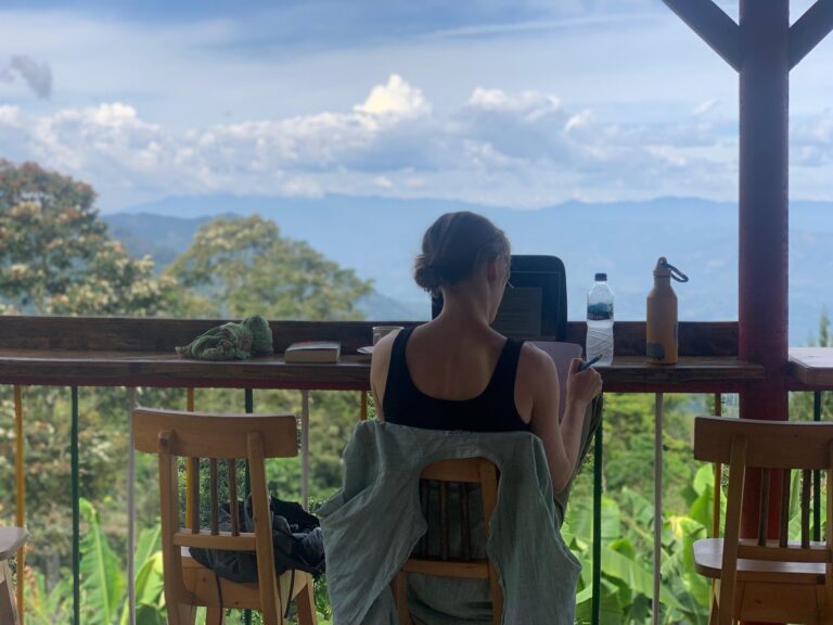 View from a balcony with a person working on a laptop in Colombia. Blue sky, greenery.